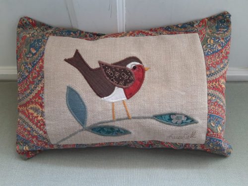 Robin cushion facing right in red and green.