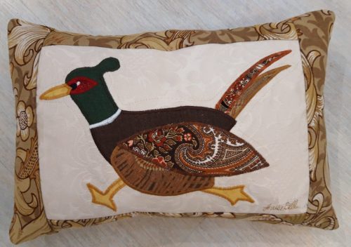 Pheasant cushion, running left. Vintage Morris Golden Lily border, smooth ochre back. Cream textured ground with appliqué