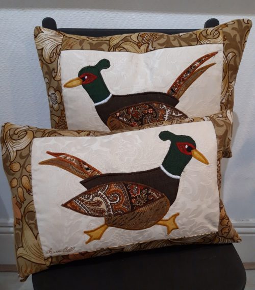 Pair of Pheasant cushions, one running right and one left. Vintage Morris Golden Lily border, smooth ochre back. Cream textured ground with applique