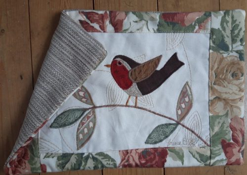 Robin on a branch facing right cushion, detail